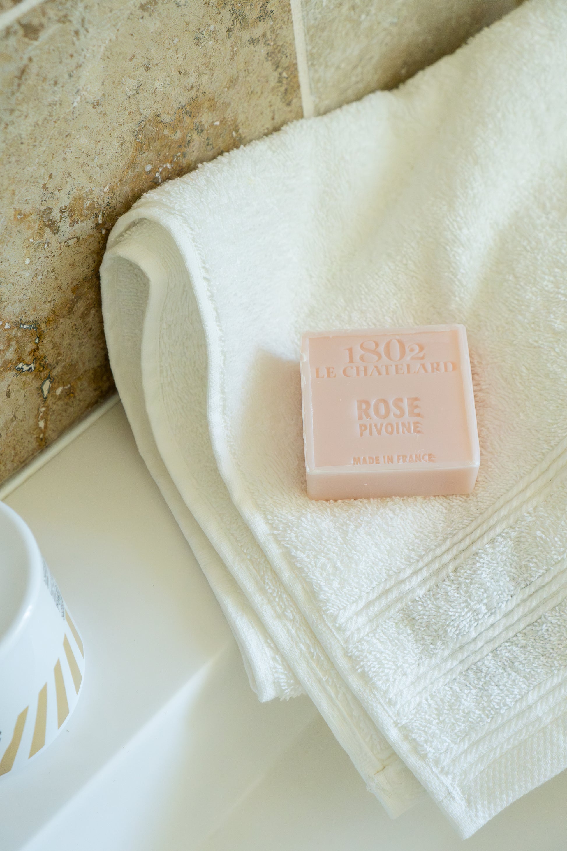 Bar of soap on a white towel with a textured wall background