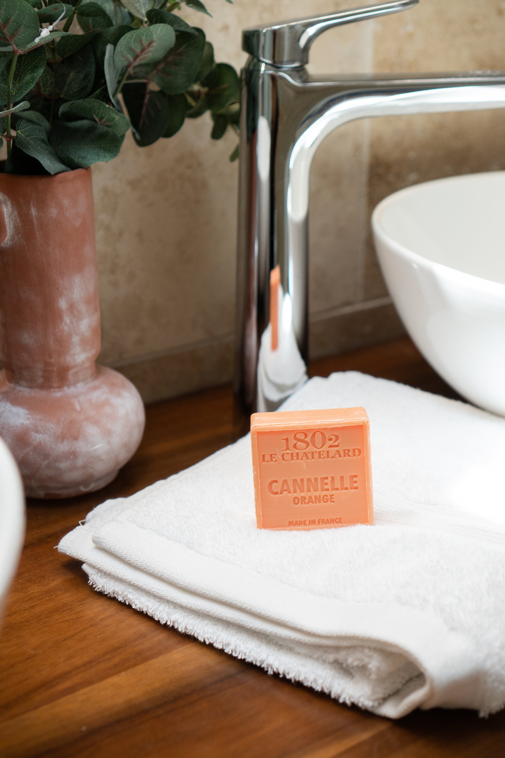 Orange soap bar on a white towel with a bathroom setting in the background