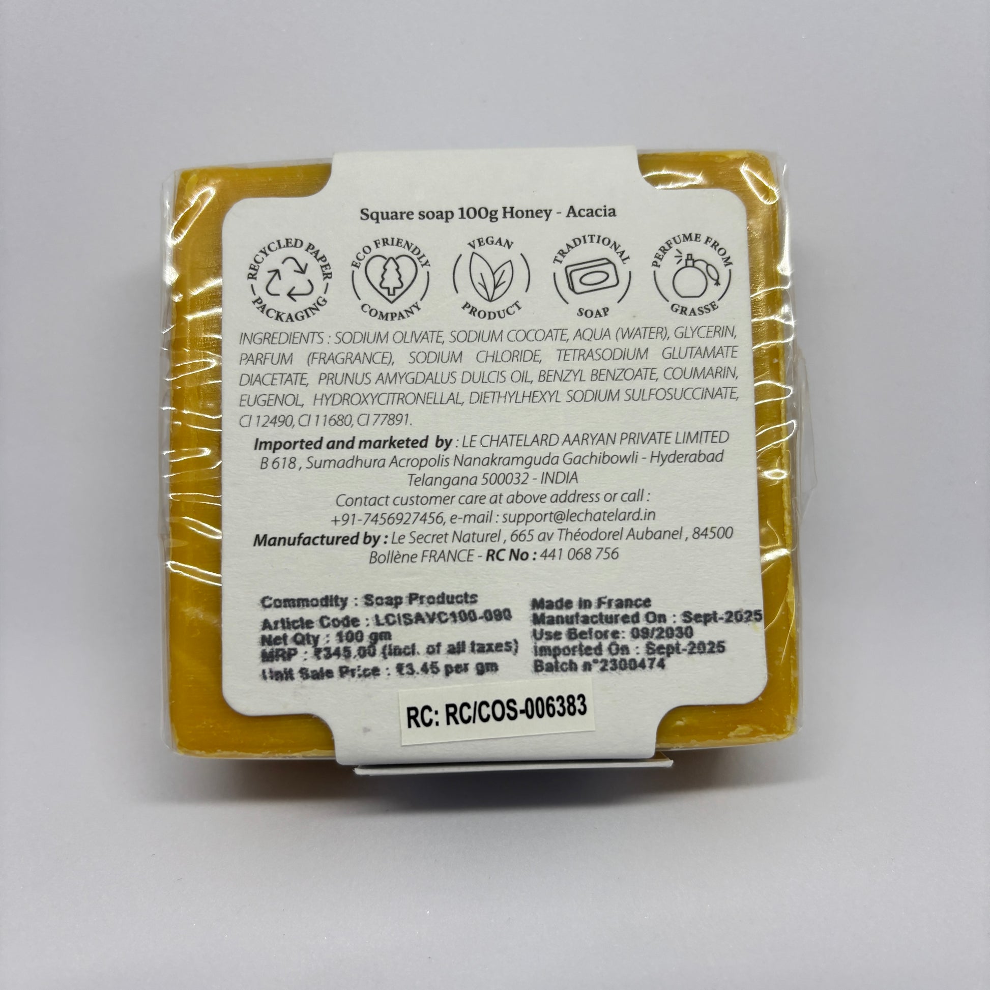 Bar of soap with packaging displaying branding and product details on a gray background