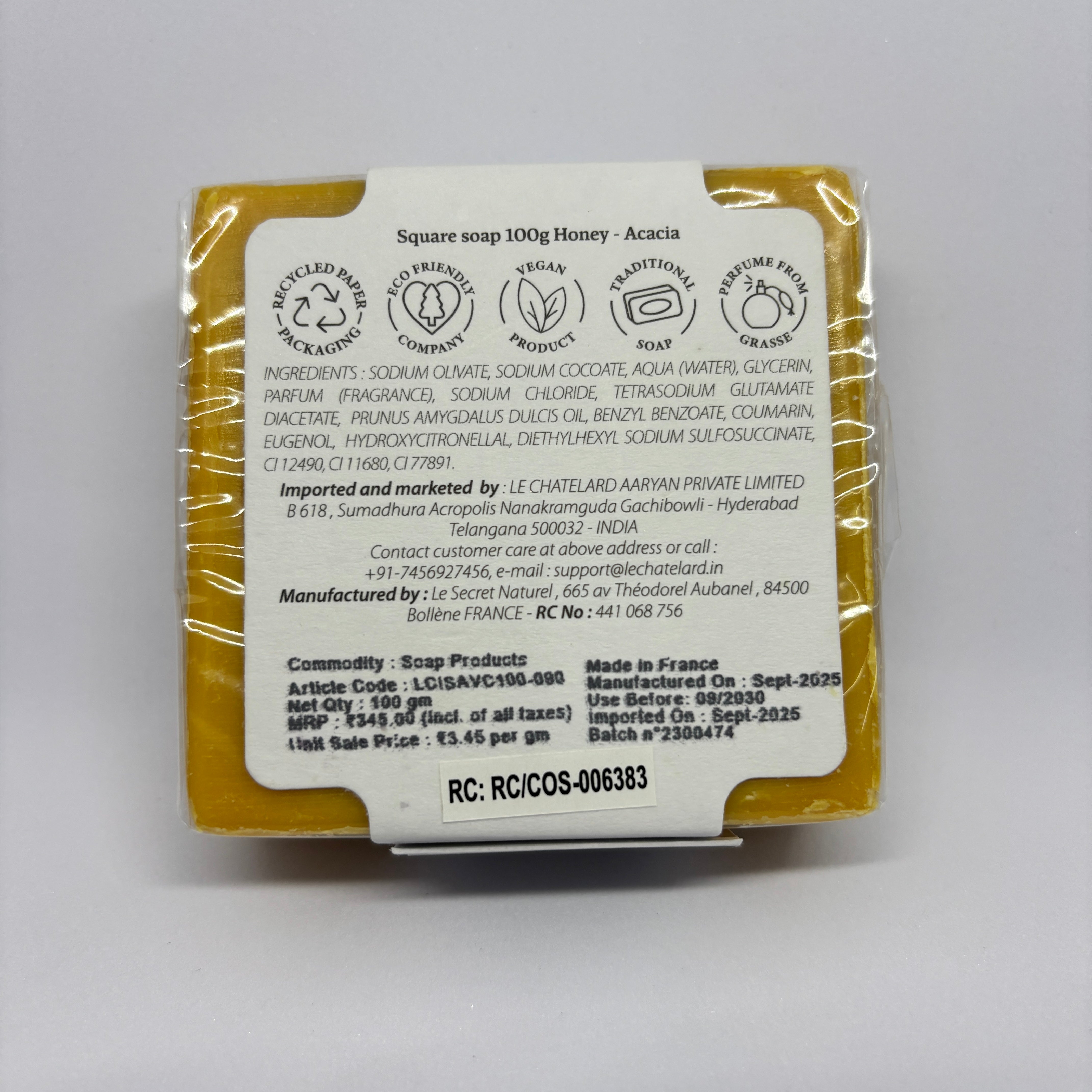 Bar of soap with packaging displaying branding and product details on a gray background